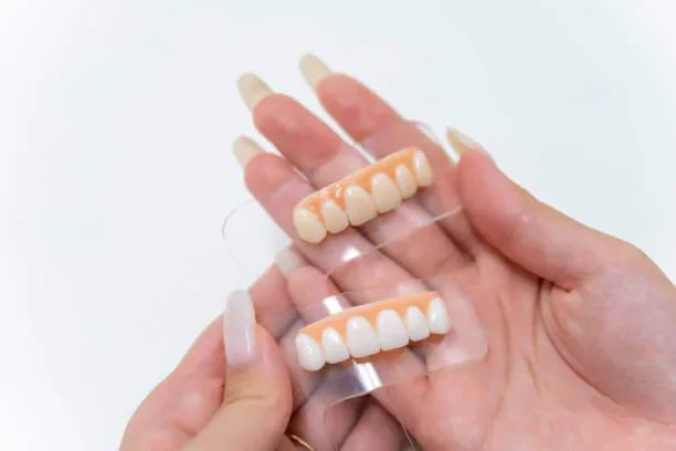 a person holding two tooth color samples,.