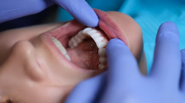 a pair of hands with gloves examining a patient's teeth