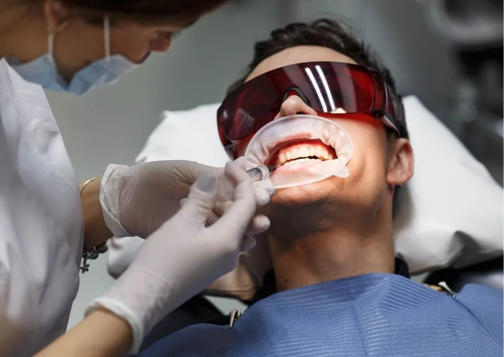 Patient receiving professional teeth whitening treatment to compare the effectiveness of in-office whitening versus whitening strips.