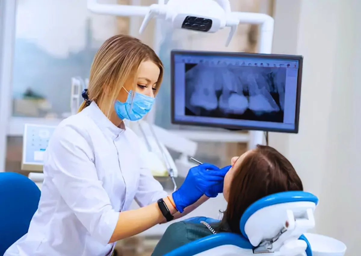 Dentist examining a patient and reviewing dental X-rays while discussing affordable dental implant options.